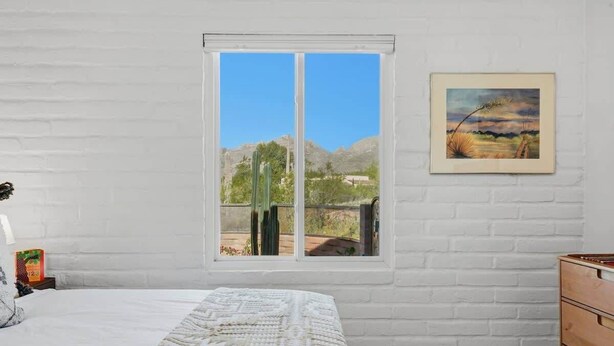 A bedroom with a bed, a window with a view of mountains, and a framed painting on the wall. - Catalina Foothills Luxe Retreat with Heated Pool! (Tucson)