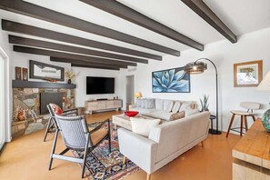 A modern living room with a fireplace, a sofa, a coffee table, and a TV. - Catalina Foothills Luxe Retreat with Heated Pool! (Tucson)