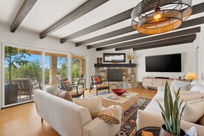 A spacious living room with a fireplace, a large flat-screen TV, and a ceiling with exposed beams. - Catalina Foothills Luxe Retreat with Heated Pool! (Tucson)
