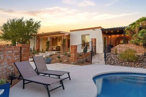 A poolside area with lounge chairs, a brick house, and a pool. - Catalina Foothills Luxe Retreat with Heated Pool! (Tucson)