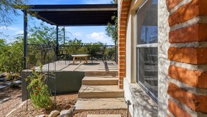 A patio with a table and chairs, a covered area, and a brick wall. - Catalina Foothills Luxe Retreat with Heated Pool! (Tucson)