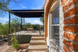 A patio with a table and chairs, a covered area, and a brick wall. - Catalina Foothills Luxe Retreat with Heated Pool! (Tucson)