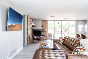 Ein modernes Wohnzimmer mit einer Ledersofa, einem Kamin und einem großen Fernseher an der Wand.