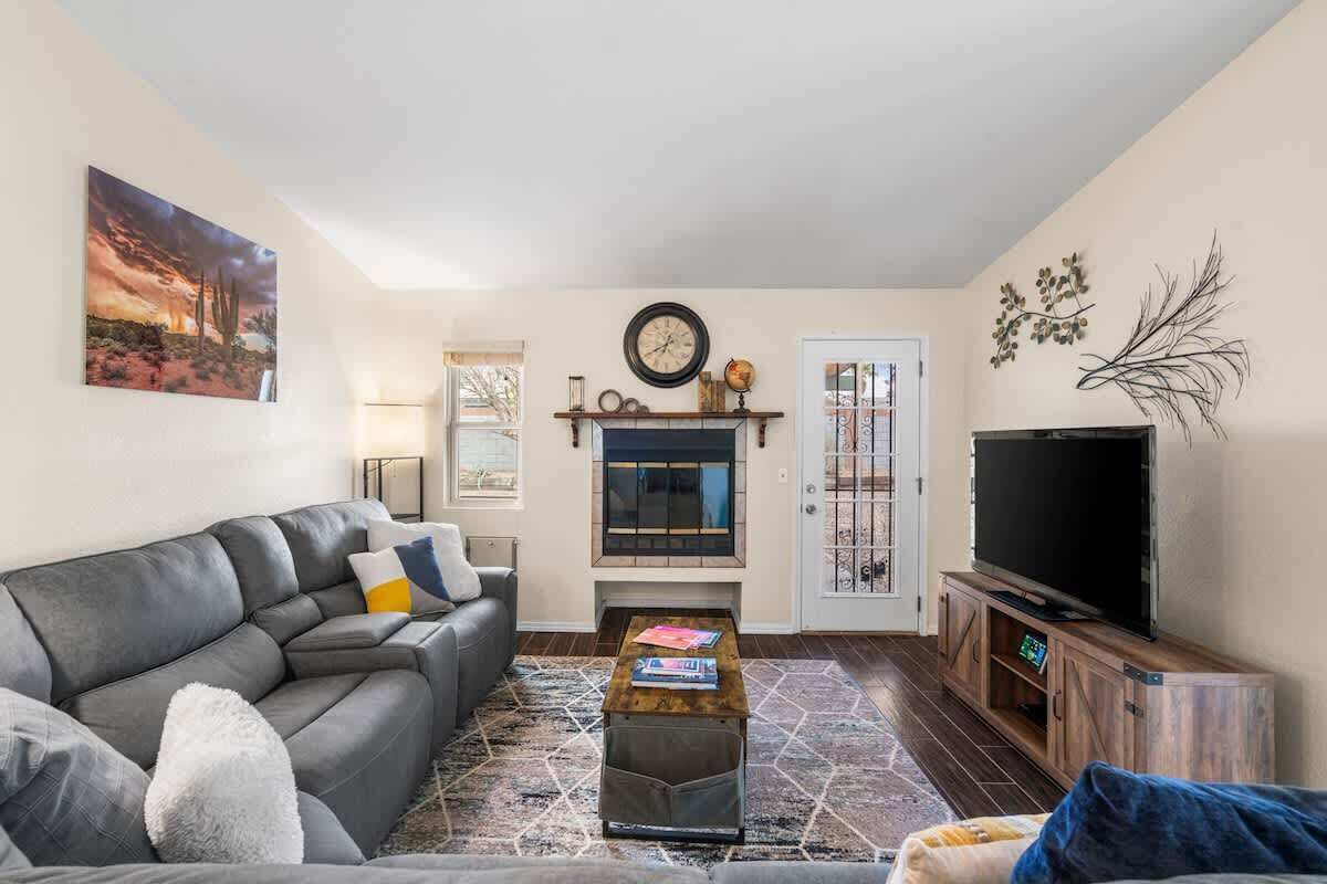 A living room with a sofa, a coffee table, a fireplace, a television, and a door with a decorative gate.