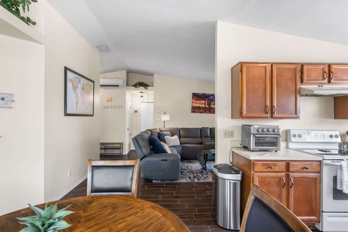 A compact living space with a dining area, kitchenette, and a sofa in the background.