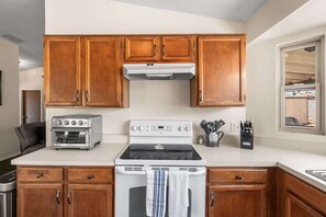 A kitchen with wooden cabinets, a built-in oven, a stove, and a window. - Cozy & Pet Friendly & Peloton! (Tucson)