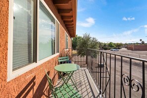 Ein Balkon mit Tisch und Stühlen, einem Geländer und Blick auf eine Straße.