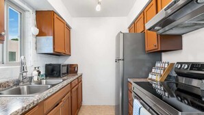 A kitchen with wooden cabinets, stainless steel appliances, a microwave, and a built-in oven. - Sunny & Bright Charm with Community Pool (Tucson)