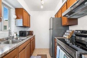 Eine Küche mit Holzausstattung, Edelstahlgeräten, einer Mikrowelle und einem eingebauten Backofen.