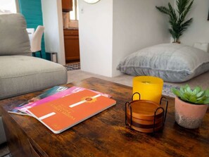 Ein Wohnzimmer mit einer Couch, einem Couchtisch mit einer Zeitschrift, einer Kerze und einem Topf mit Pflanze.