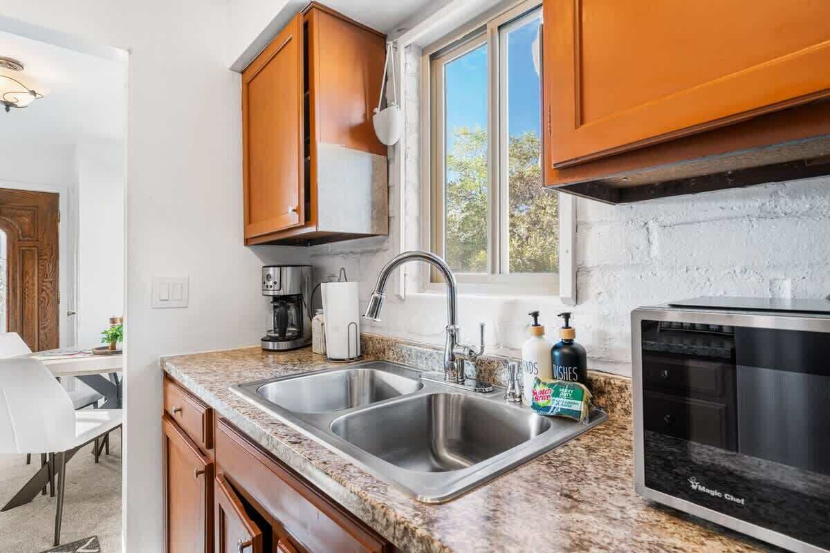 A kitchen with granite countertops, stainless steel appliances, wooden cabinets, and a window with a view.