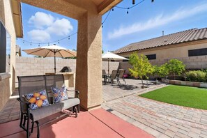 An outdoor patio with a covered seating area, string lights, and a well-maintained lawn. - Desert Solace Retreat w/Pool/Spa (Tucson)