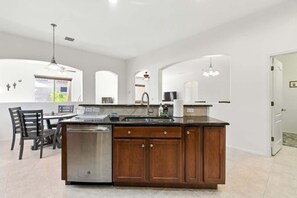 A kitchen with a central island, a dishwasher, and a dining area with chairs. - Desert Solace Retreat w/Pool/Spa (Tucson)