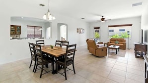 A spacious living area with a dining table, chairs, a sofa, and a television. - Desert Solace Retreat w/Pool/Spa (Tucson)