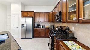 A kitchen with wooden cabinets, a stainless steel refrigerator, a microwave, and a stove. - Desert Solace Retreat w/Pool/Spa (Tucson)