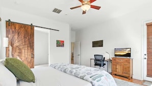 A bedroom with a bed, a desk, a television, and a sliding door. - Desert Solace Retreat w/Pool/Spa (Tucson)