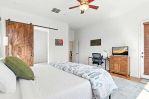 Ein Schlafzimmer mit Bett, Schreibtisch, Fernseher und einer Schiebetür.
