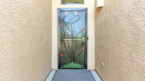A door with a geometric design, a small window above it, and a mat at the entrance. - Desert Solace Retreat w/Pool/Spa (Tucson)