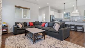 Ein modernes Wohnzimmer mit einem Ecksofa, einem Couchtisch und einer Küche im Hintergrund.