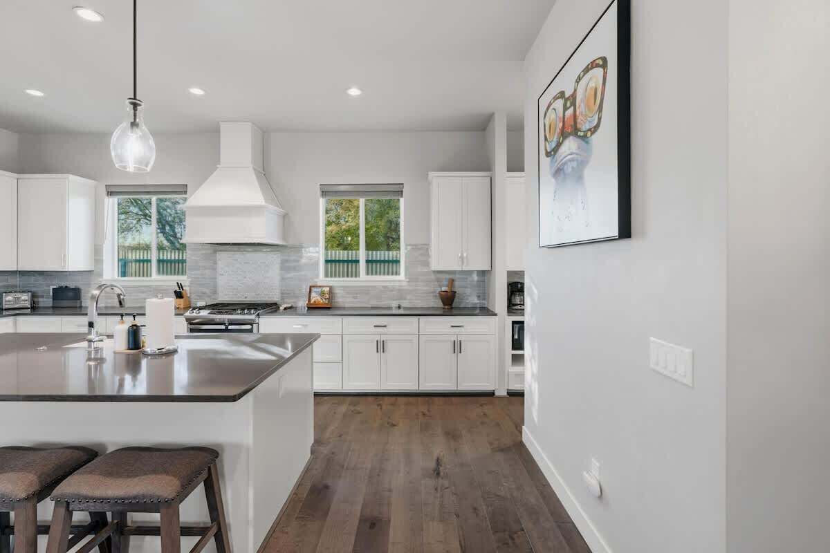 Une cuisine moderne avec des meubles blancs, un îlot central et un luminaire suspendu.