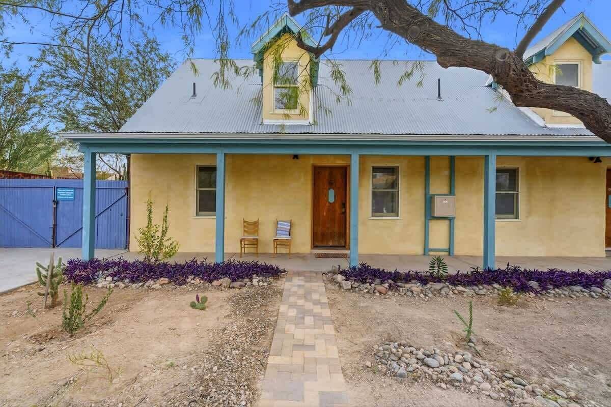 Une maison à deux étages avec un toit bleu et une véranda à l’avant.