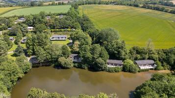 Luchtbeeld van een woongebied met huizen, omringd door weelderig groen en een vijver.