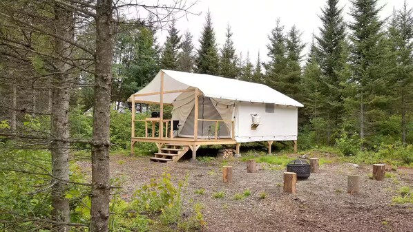 A cabin with a wooden deck, a covered porch, and a tent-like structure.