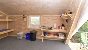 Una habitación pequeña y cerrada con ventana, un calentador y una estantería con diversos objetos.