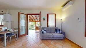 Una habitación con sofá, una mesa de comedor con sillas, zona de cocina y vistas al exterior.