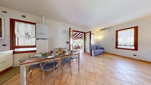 Cocina compacta con comedor, sofá y vista a través de una puerta abierta.