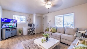Ein Wohnzimmer mit Fernseher, Sofa, Couchtisch und Schreibtisch.