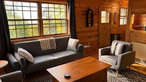 Una habitación acogedora estilo cabaña, con un sofá, un sillón y una mesa de centro.