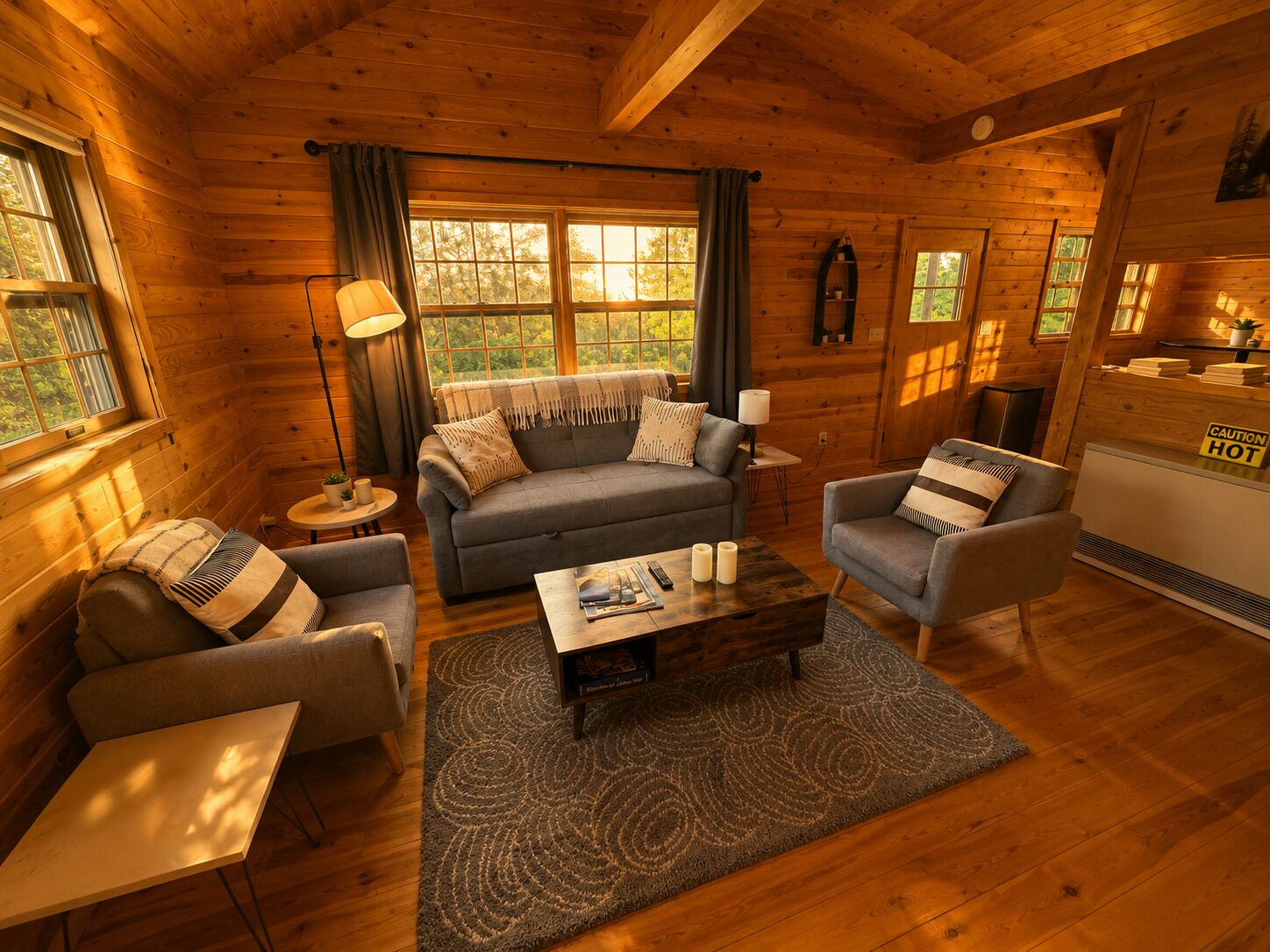 A cozy log cabin interior with a sofa, armchairs, a coffee table, and a fireplace.