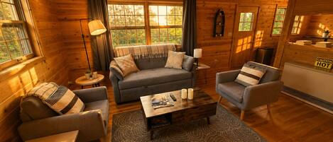 A cozy log cabin interior with a sofa, armchairs, a coffee table, and a fireplace.