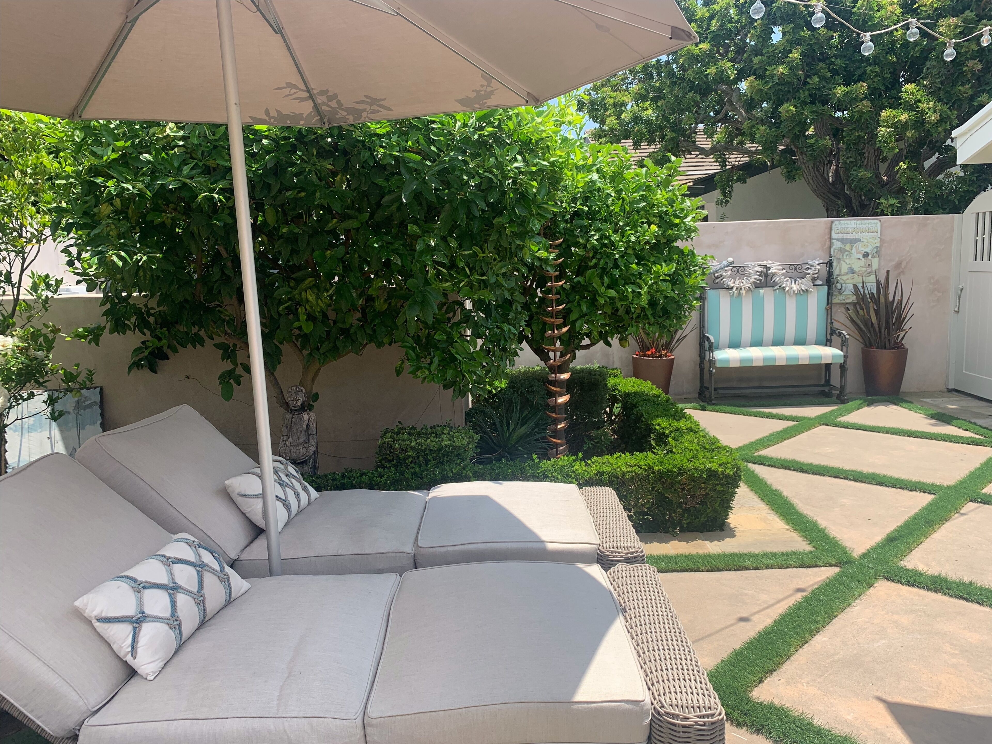Eine Terrasse mit einer Sitzecke, einem Baum und einer Bank.