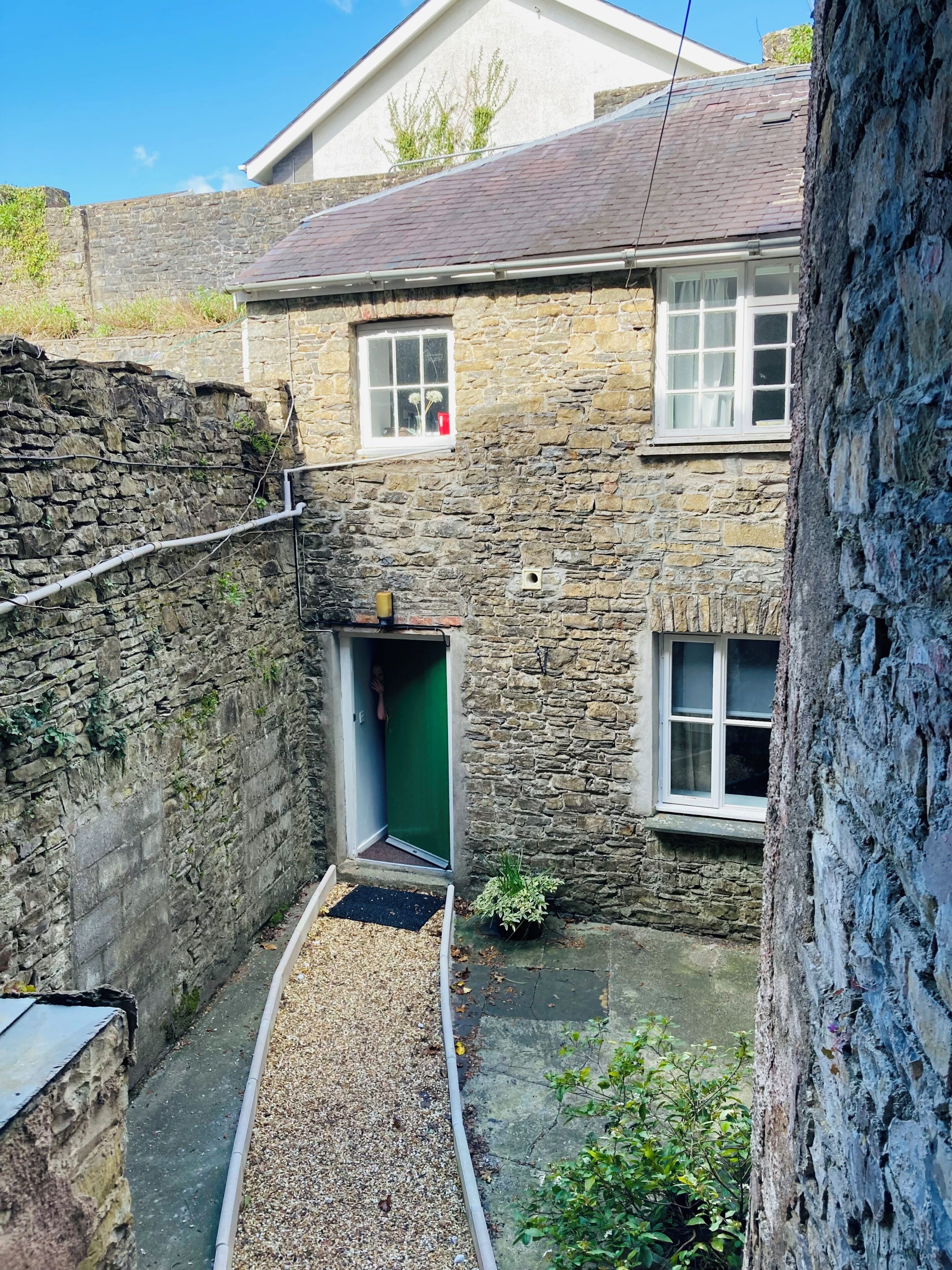 A stone building with a narrow alleyway leading to a door.