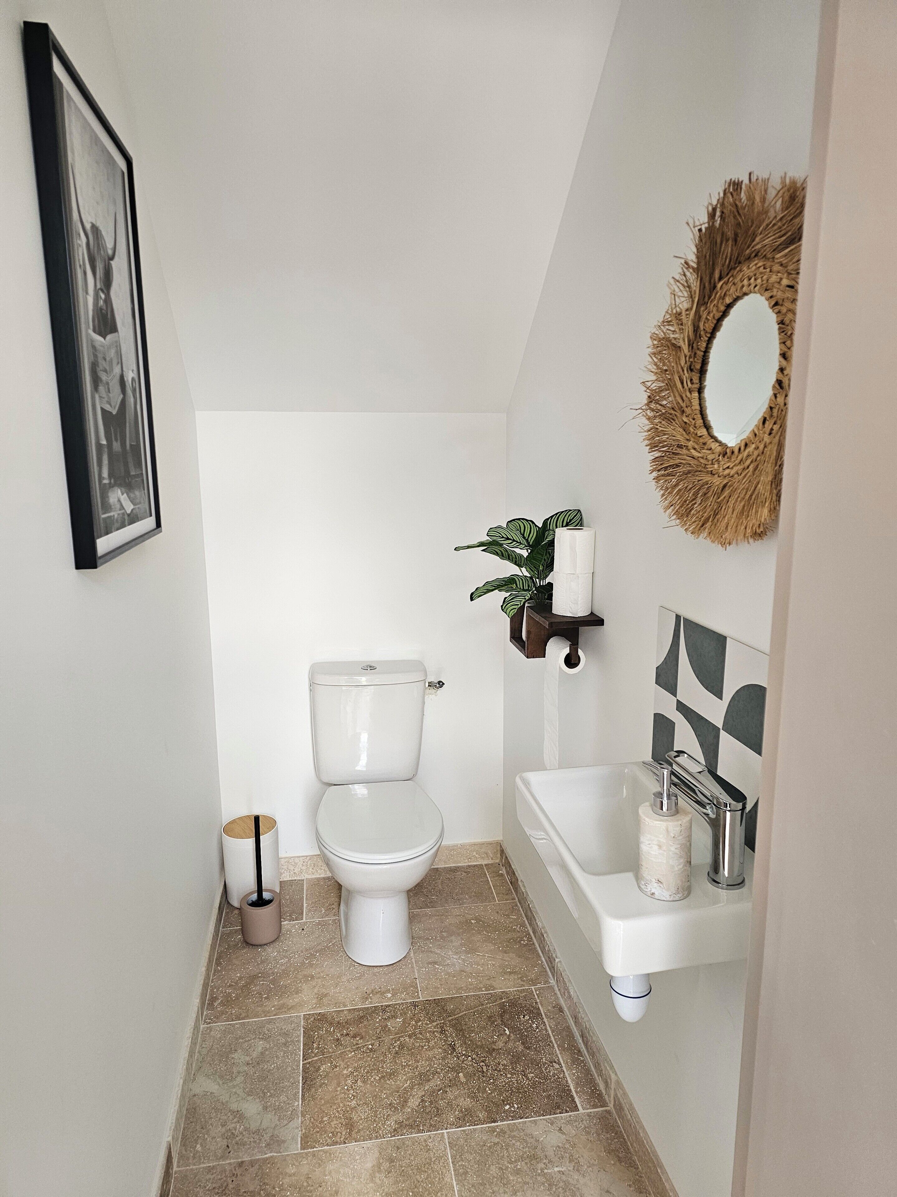 A bathroom with a toilet, sink, and mirror.