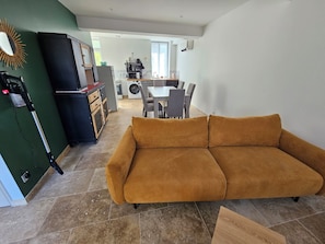 A living room with a sofa, a dining area with chairs, a kitchen with appliances, and a washing machine. - 25 minutes from Le Pal Park, 1 km from downtown Bourbon-Lancy (Bourbon-Lancy)