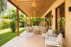 A covered patio with two hanging chairs, a white sofa, and a small table. - 3 Bed, 2 Bath, AC, Family& Pet-Friendly Modern Jungle Oasis w/Private Pool (Puerto Viejo de Telemanca)