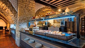 Een ontbijtbuffet met brood, gebak en een stenen boog.