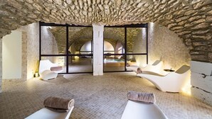 Een spa-ruimte met een stenen plafond, grote ramen en moderne zitplaatsen.