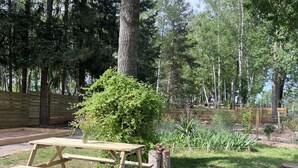 Piknikpöytä metsäisellä alueella, jossa on puinen aita ja pieni pensas.