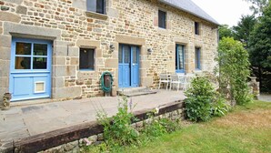 A stone building with blue doors and windows, a small outdoor seating area, and a garden. - Historic house, parking, pets welcome (MONTBRAY)