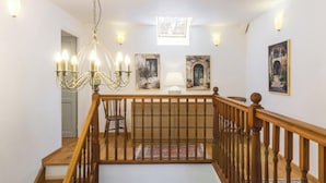 A wooden staircase leading to a loft area with a chandelier, framed artwork, and a view of the lower level. - Historic house, parking, pets welcome (MONTBRAY)