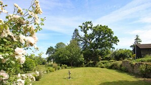 A well-maintained grassy lawn with a fountain, surrounded by trees and a rustic building. - Historic house, parking, pets welcome (MONTBRAY)