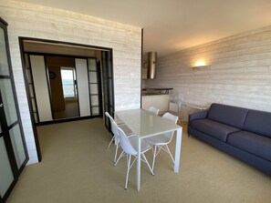 A modern living room with a dining area, a sofa, and a kitchen in the background. - T1 Apartment, sea view - 2 guests (Arcachon)