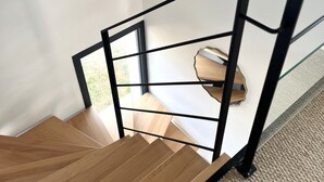 Una escalera de madera con barandal de metal negro que lleva a una habitación con ventana.