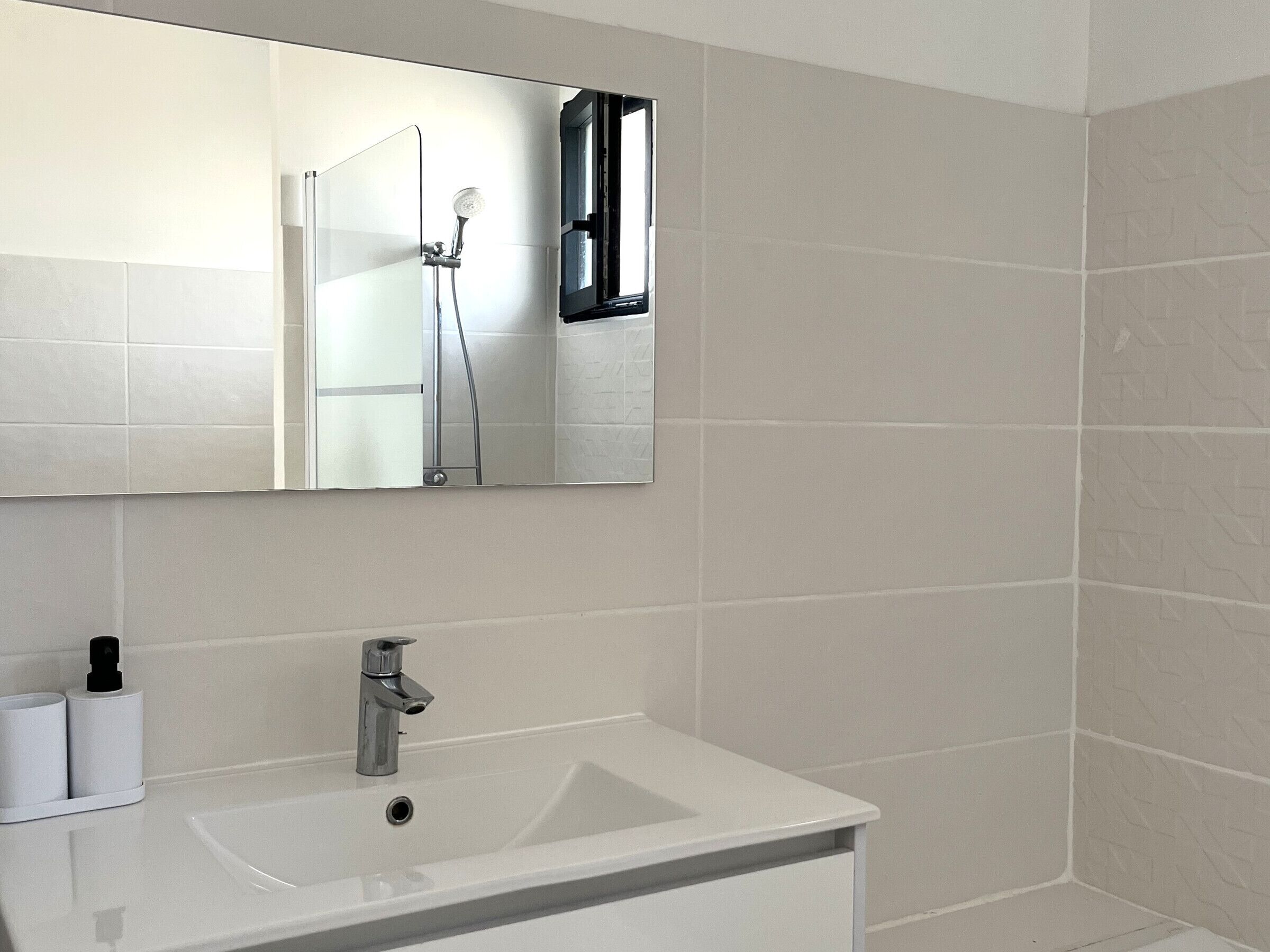 A bathroom with a white sink, a mirror, and a shower.
