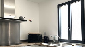 Una cocina moderna con extractor de acero inoxidable, microondas y lavavajillas.