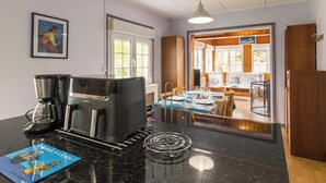 Un vestíbulo de hotel con una cafetera, un cuadro enmarcado en la pared y una zona de comedor con una mesa para dos.